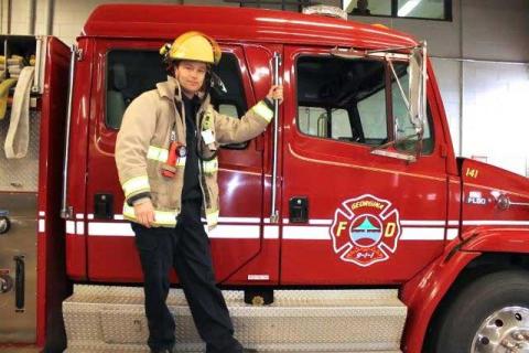 Fire Fighter in uniform standing on fire truck